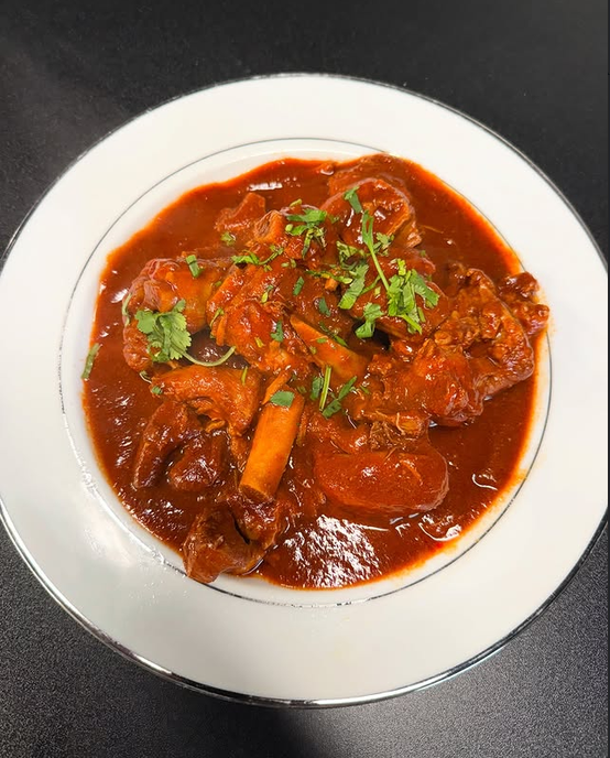 Chile colorado: res en salsa roja de chile guajillo, servida en plato hondo con cilantro