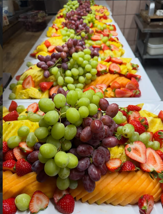 Charolas de fruta de temporada con uva, fresa, piña y melón, preparadas en la cocina
