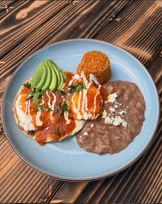 Huevos rancheros en salsa roja con aguacate, crema, arroz mexicano y frijoles refritos