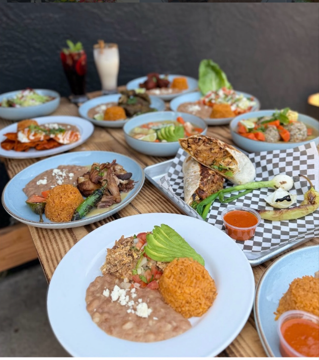 Mesa de madera con platillos mexicanos, arroz, frijoles y aguas frescas