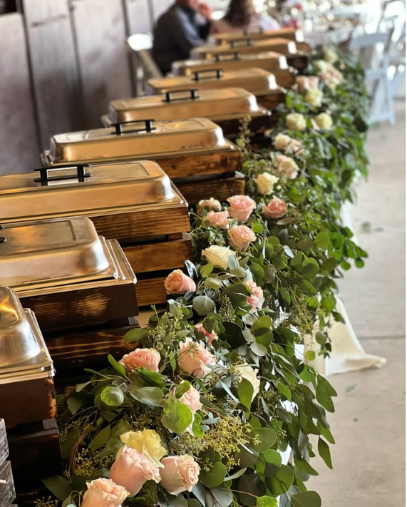 Buffet elegante con mantel azul marino y guirnalda de rosas blancas